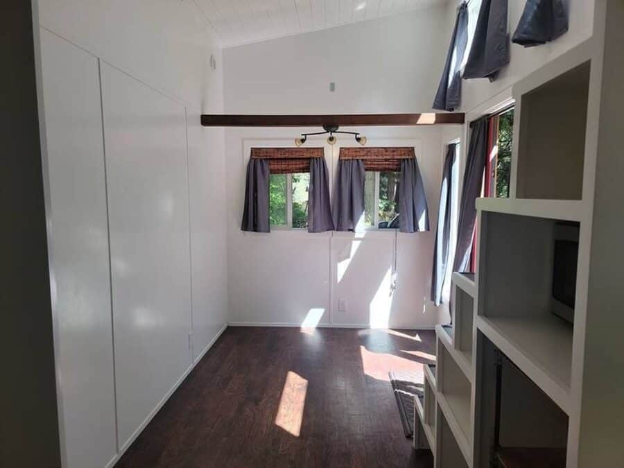 Cozy tiny house interior with large windows, ample storage, and natural light.