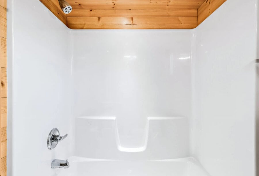Small bathroom shower in a tiny house with wooden accents.
