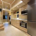 Bright tiny house kitchen with large windows and modern appliances.