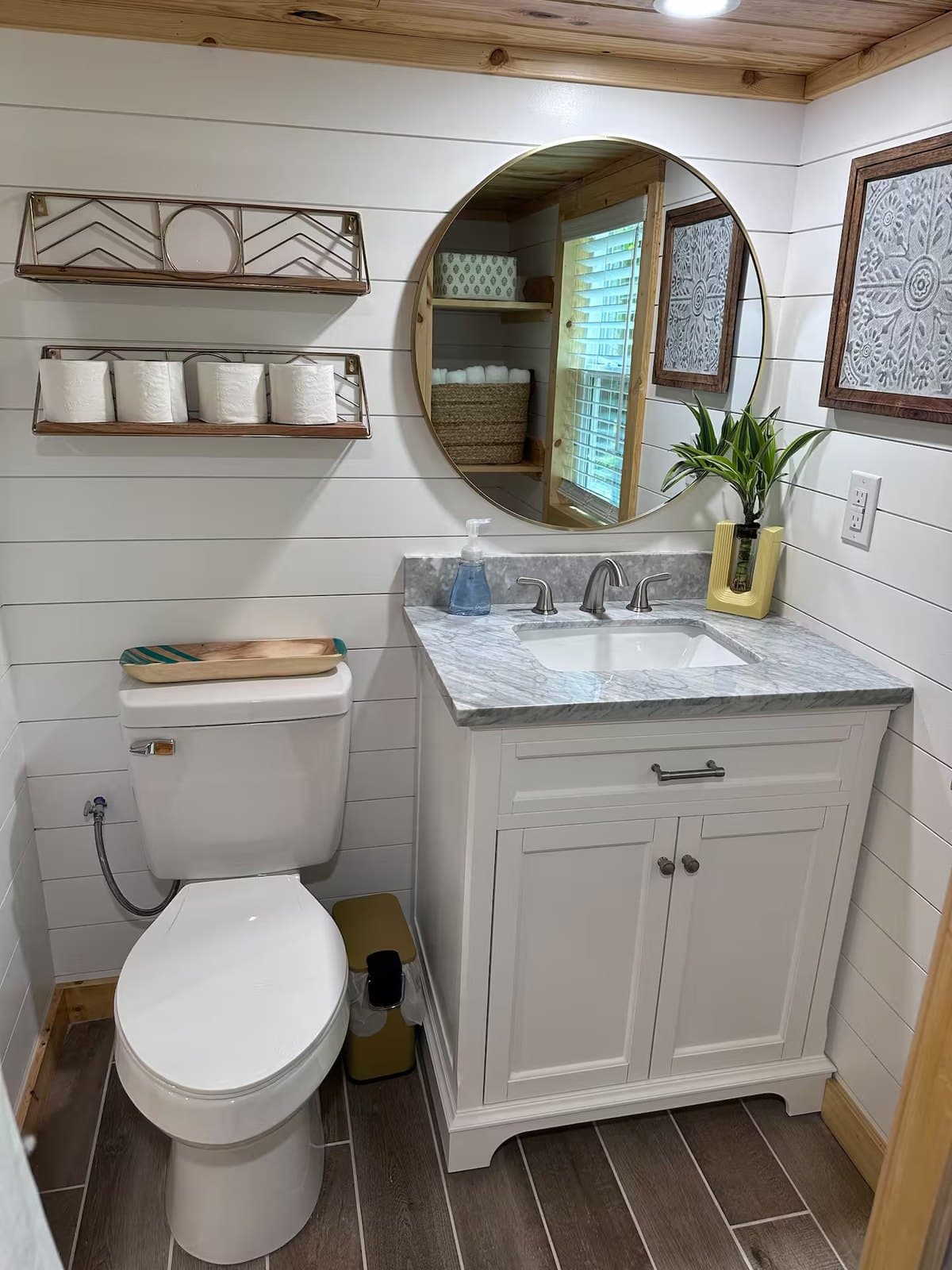 Rasa tiny home bathroom with a marble-top vanity, round mirror, and flush toilet
