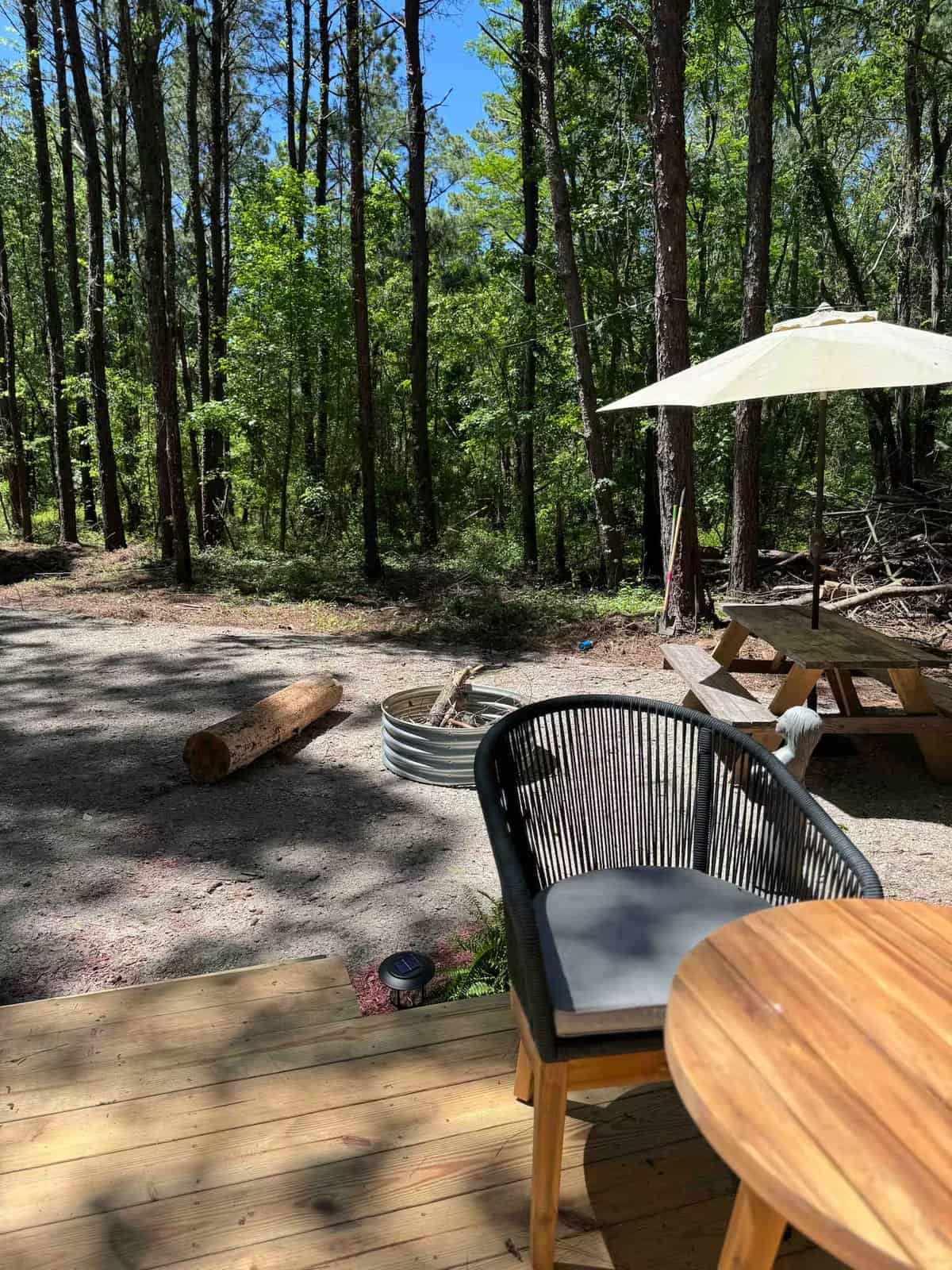 View from the Rasa tiny home deck toward the fire pit and picnic table among the trees