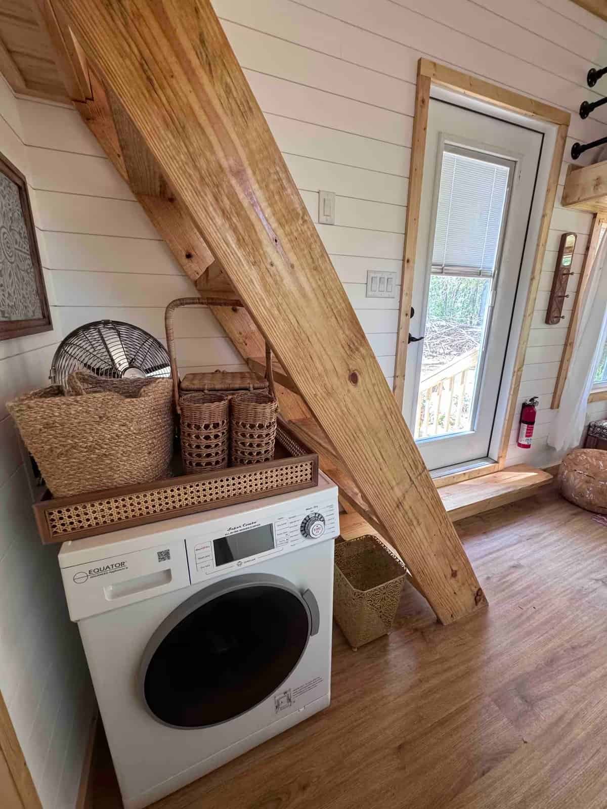 Washer-dryer combo unit tucked beneath the loft ladder in the Rasa tiny home