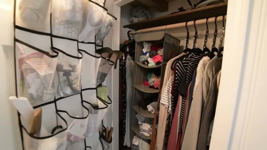 Full closet with hanging clothes and door organizer in a tiny house