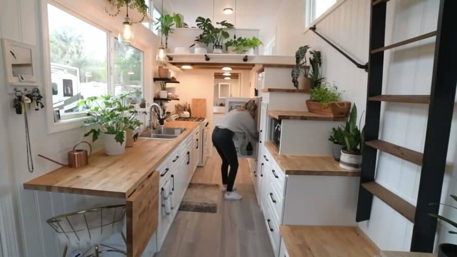Galley kitchen with butcher block counters and storage staircase in a tiny house