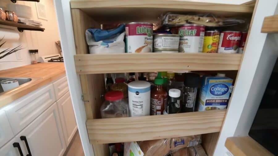Pull-out pantry built into tiny house storage stairs