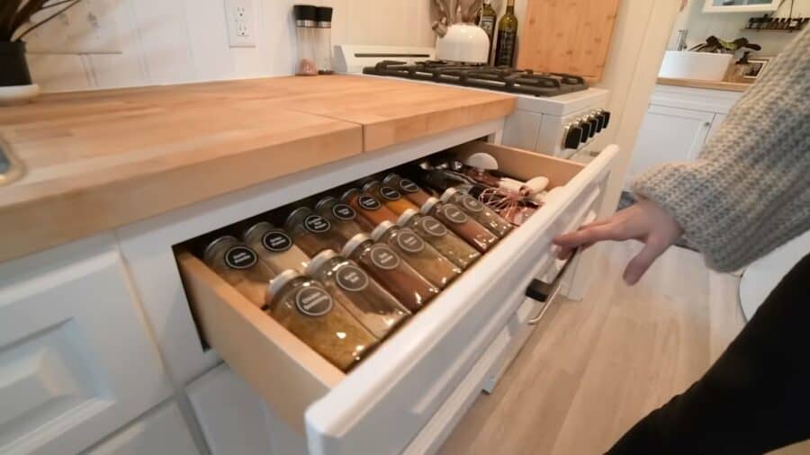 Spice drawer with labeled jars in a tiny house kitchen