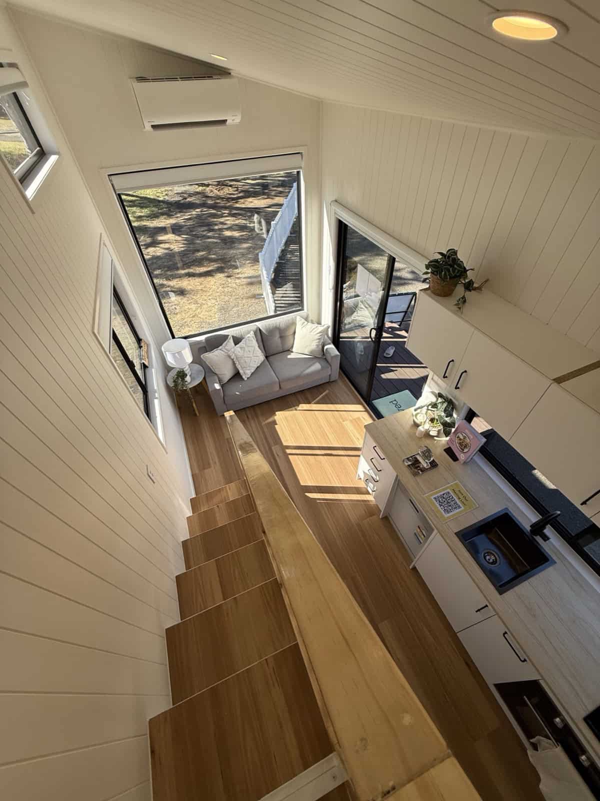 View from the Cabarita loft looking down over the staircase, living area, and kitchen, showing the home's vaulted volume