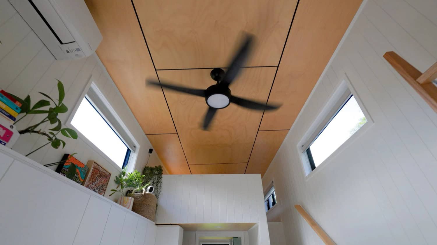 Looking up inside the Coolangatta at its two loft levels, a timber-lined ceiling, a black ceiling fan, and clerestory windows