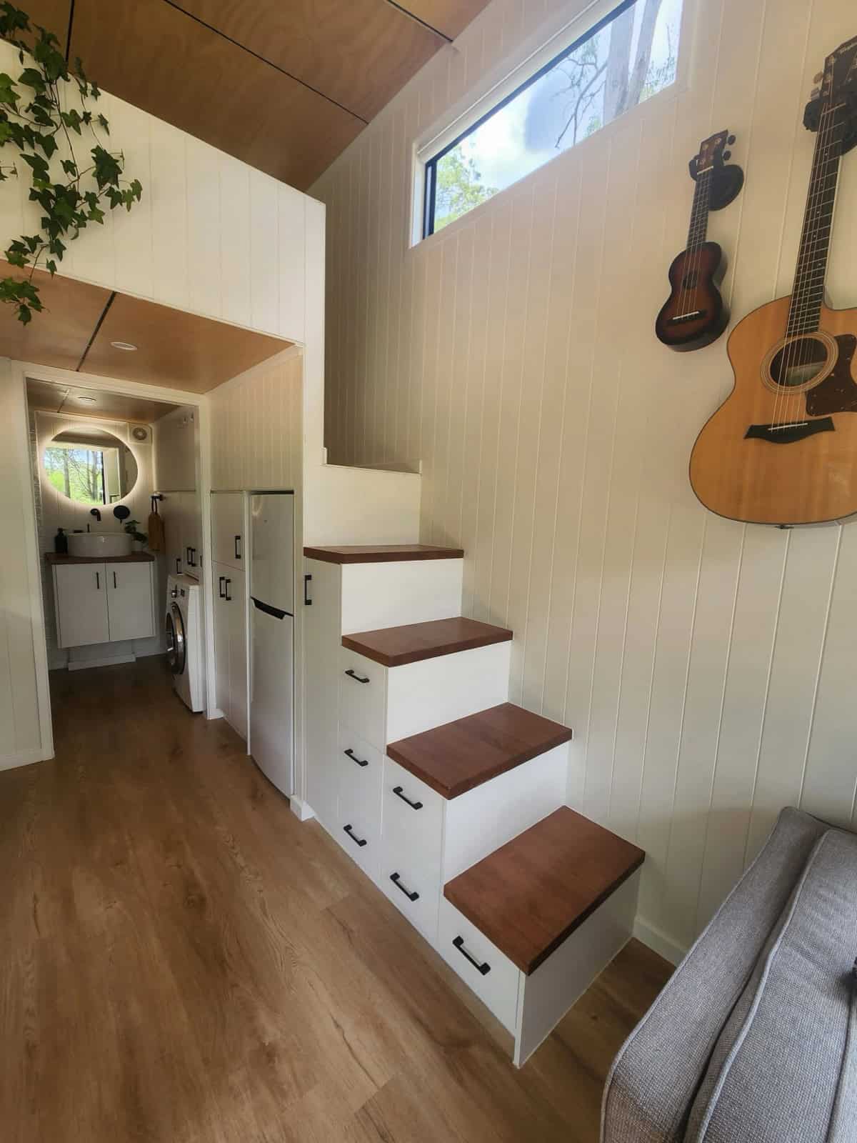 The Currumbin's storage staircase with timber treads and built-in white drawers, leading up to a standing-height loft, with the bathroom and laundry visible down the hall