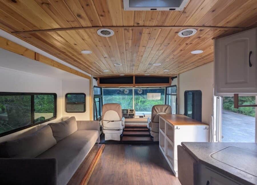 Compact tiny house living space with wooden ceiling and modern furnishings.