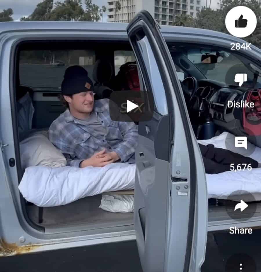 Young man relaxing inside a pickup truck converted into a tiny living space.