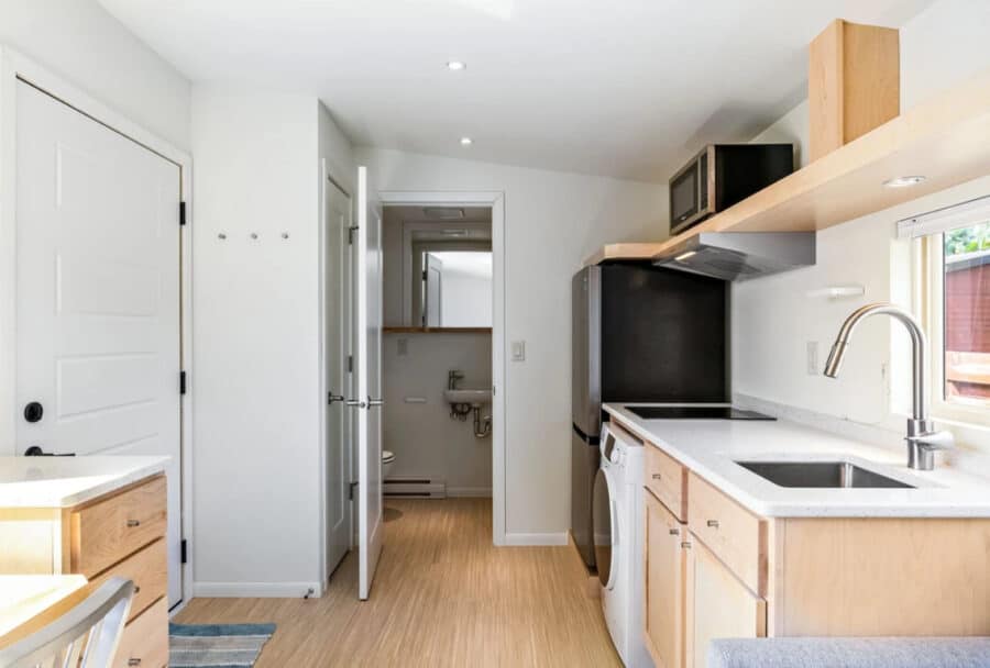 Compact tiny house kitchen with modern appliances and natural light.