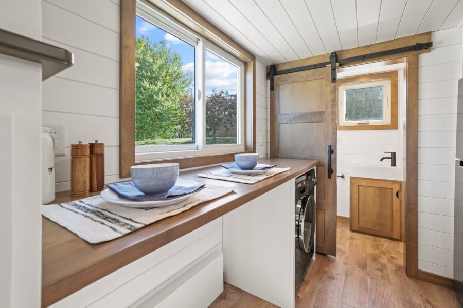 Cozy tiny home kitchen with large window and modern rustic design.
