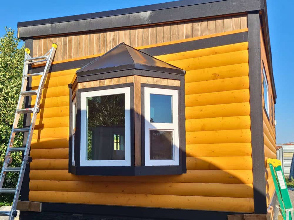 Close-up of the Black Bear cottage's bay window with a peaked metal cap and cedar log siding