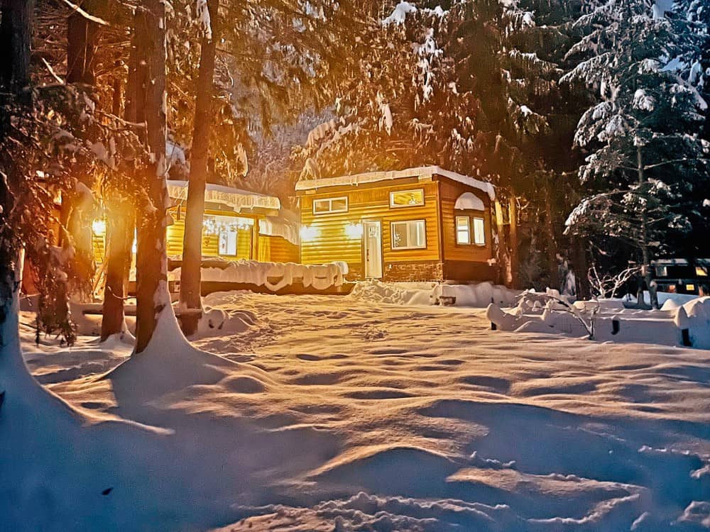 Black Bear cottage glowing warmly on a snowy evening in a forest setting