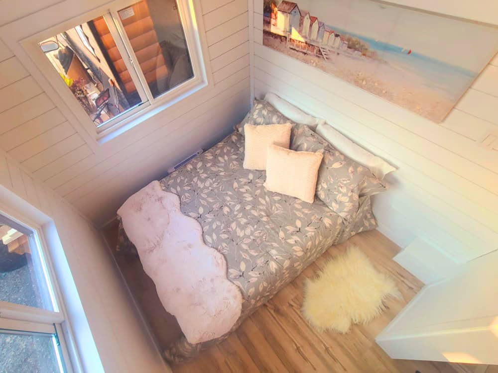 Cinnamon Bear main bedroom with a queen bed, white shiplap walls, a window, and coastal artwork