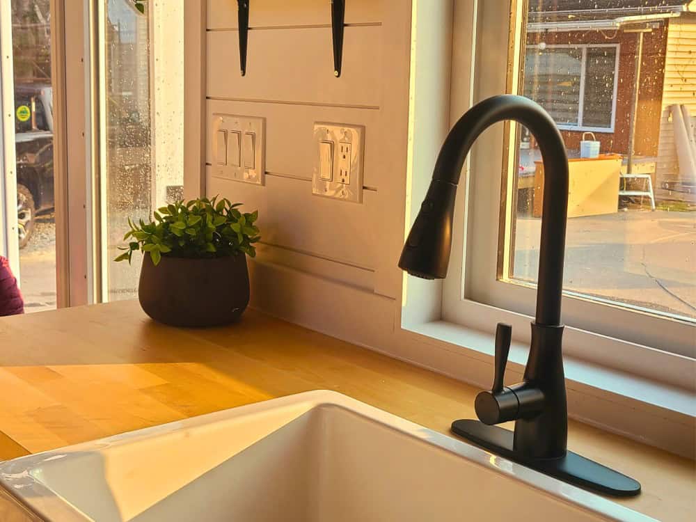 Cinnamon Bear kitchen with butcher-block counter, white farmhouse apron sink, and a black gooseneck faucet under a window