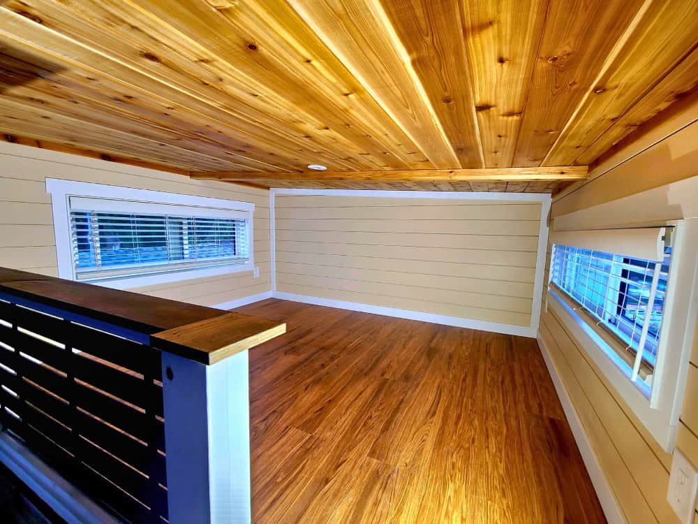 Fraser Bear loft sleeping area with a warm cedar ceiling, hardwood floor, a slatted railing, and windows on multiple sides