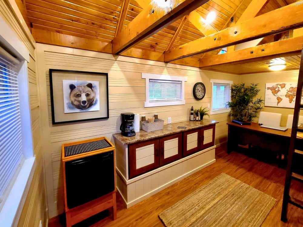 Coffee and kitchenette station inside the Honeycomb Mobile Office with granite counter, coffee maker, mini-fridge nook, and a framed bear print