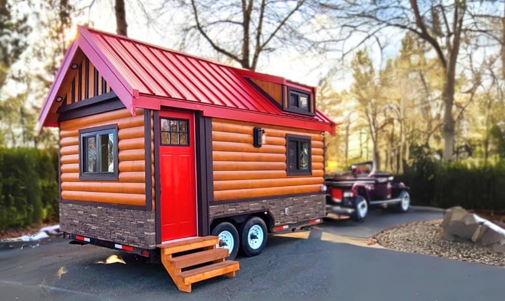 Three-quarter exterior view of the Rolling Bear Honeycomb Mobile Office showing log siding, stone skirting, and dual-axle trailer