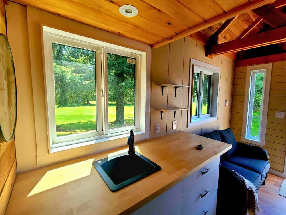 Workspace counter beneath a large window in the Honeycomb Office Farmhand, with shelving and a blue armchair