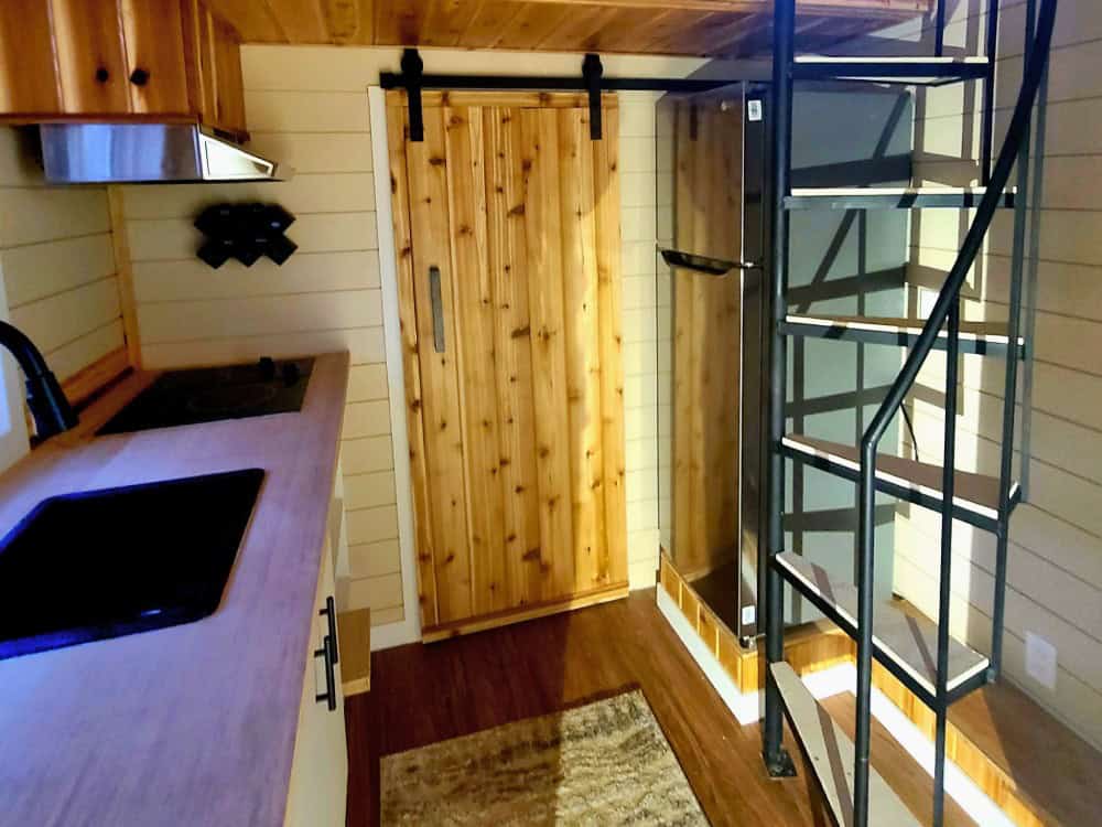 Black spiral iron staircase beside the Panda Bear kitchen and a cedar barn door leading to the bathroom