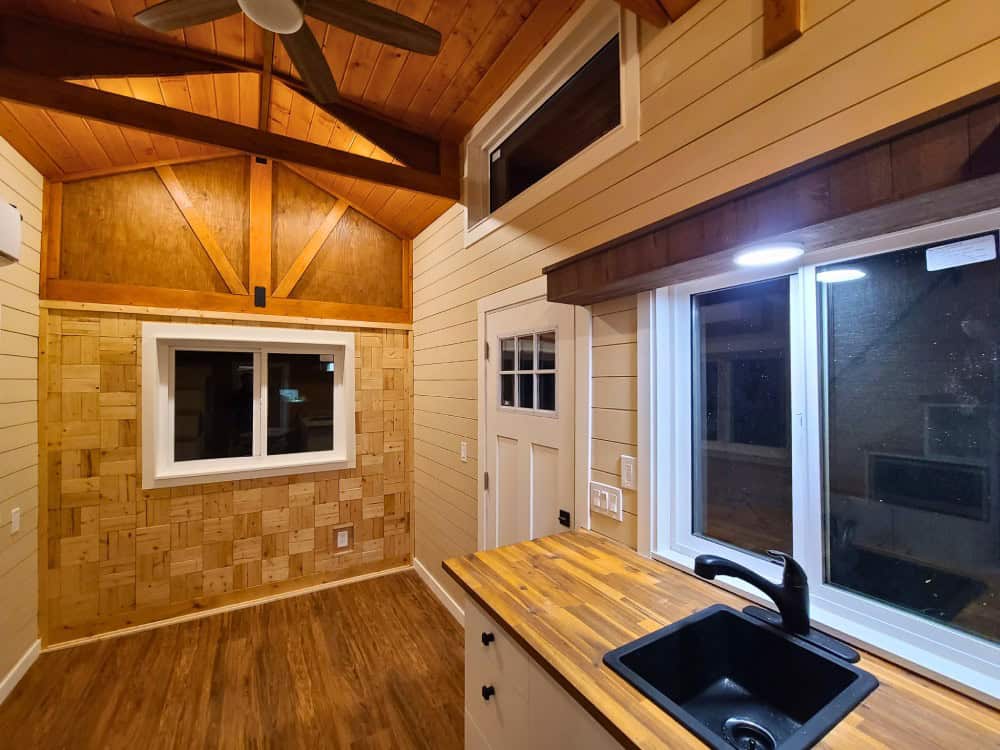 Vaulted cedar great room of the Salmon Bear with exposed timber trusses, ceiling fan, shake accent wall, and butcher-block counter