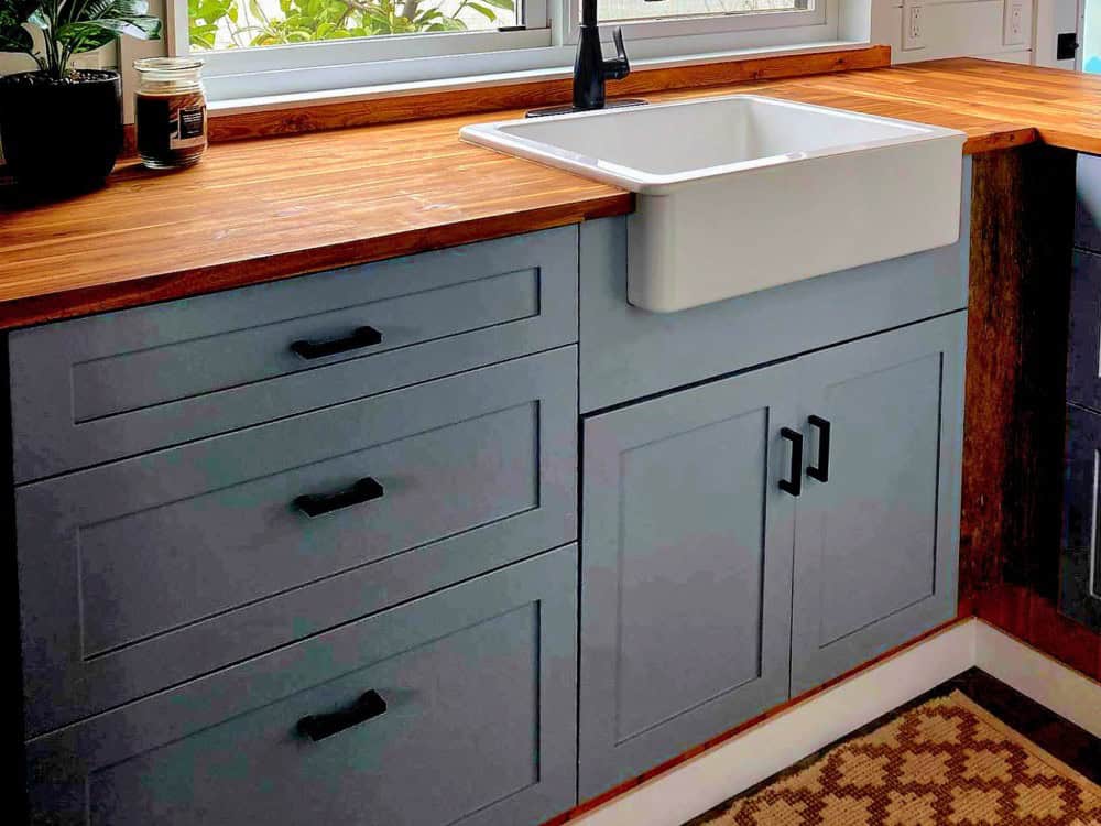 Bespoke blue-grey shaker cabinetry with black hardware and butcher-block counters beside a white farmhouse sink in the Spirit Bear