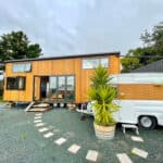 Compact tiny house with modern wooden exterior and large windows.