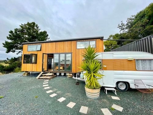 Compact tiny house with modern wooden exterior and large windows.