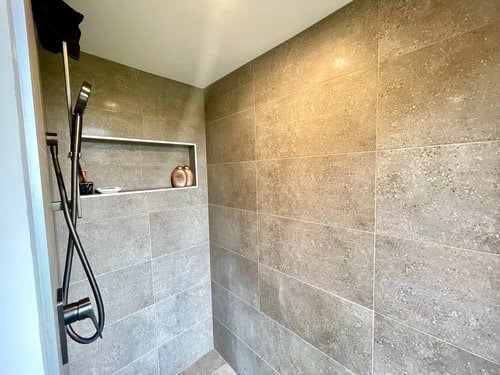 Modern tiny house shower with sleek tiles and built-in shelf.