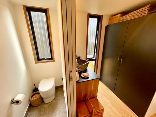 Compact tiny house interior featuring a bathroom and storage closet.