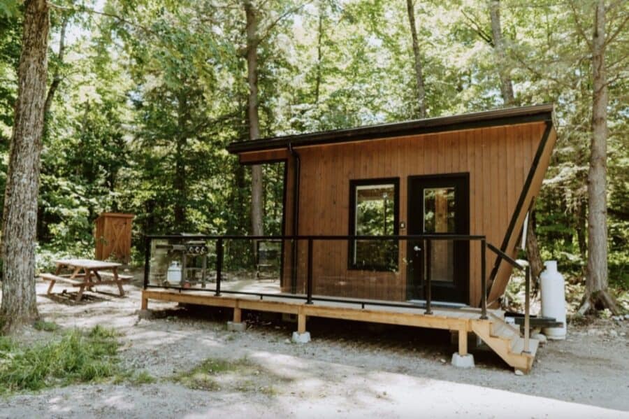 Charming tiny house in Haliburton, Ontario, featuring a modern design and cozy outdoor deck amidst l.
