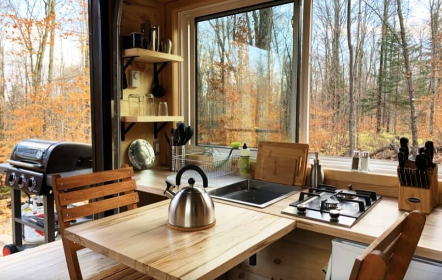 Charming tiny house kitchen with large window views of autumn trees in Haliburton, Ontario. Perfect.