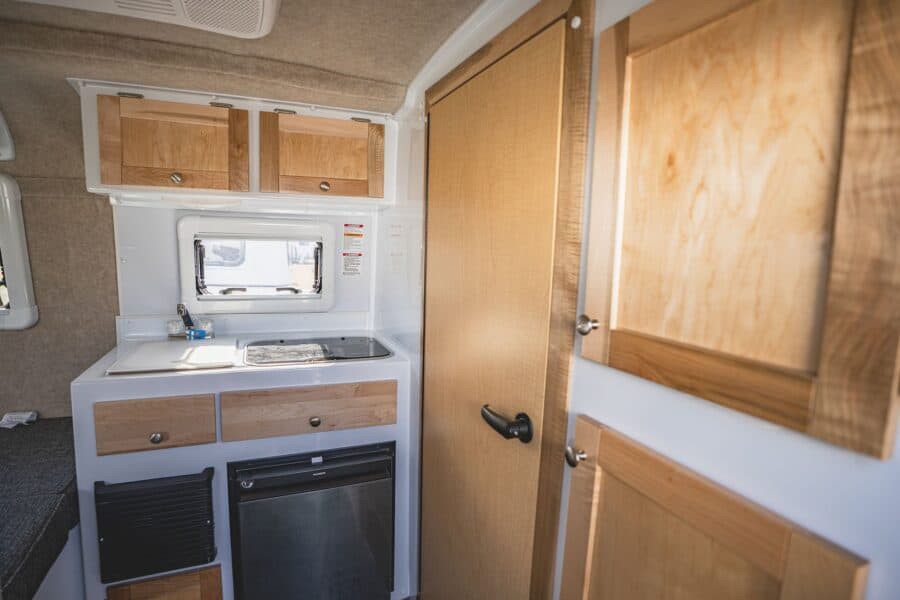 Galley sink and stove beside the wood bathroom door