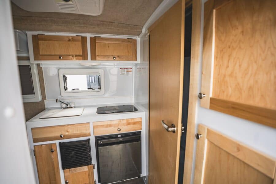 Galley sink and stove beside the wood bathroom door