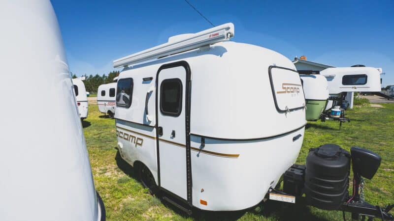 White Scamp 13 with an awning on a grassy lot