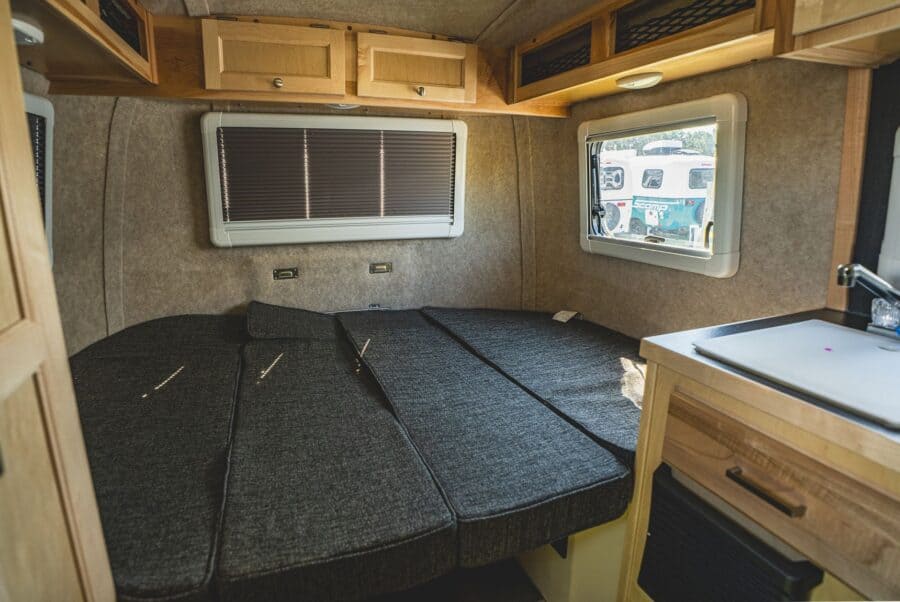 Rear bed with grey cushions and the galley