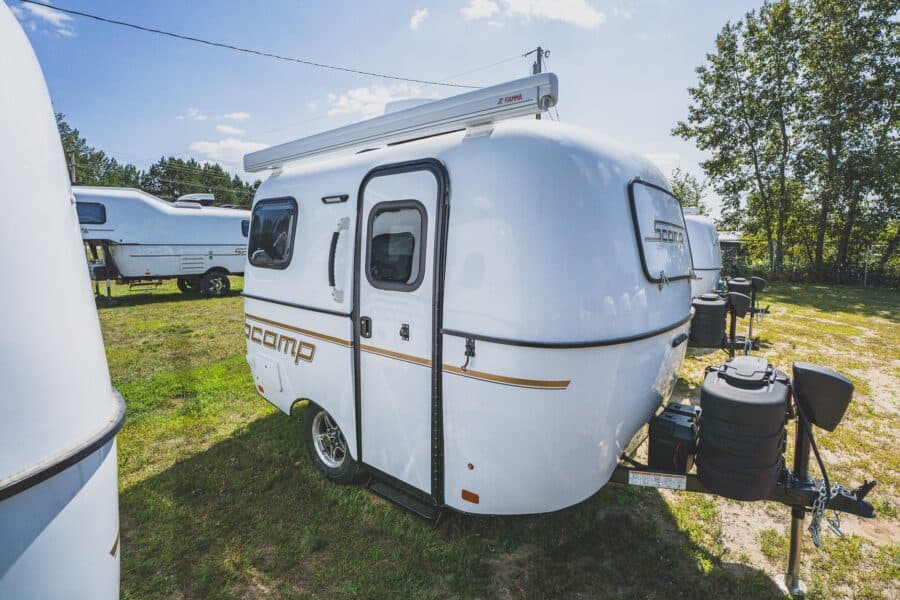 White Scamp 13 with an awning on a grassy lot