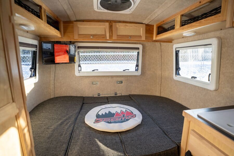 Rear dinette with windows on three sides and a wall-mounted TV