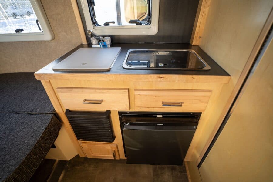Galley counter with a sink cover above the refrigerator
