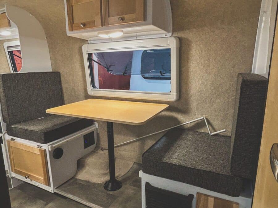 Side dinette with a light wood table and dark cushions