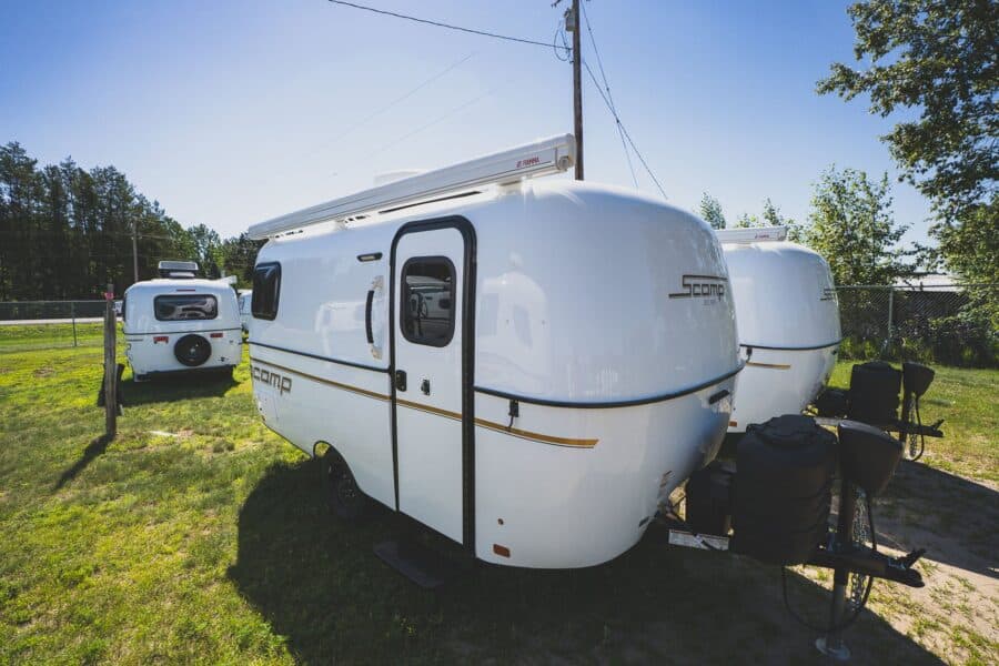 White Scamp 16 with an awning on a grassy lot