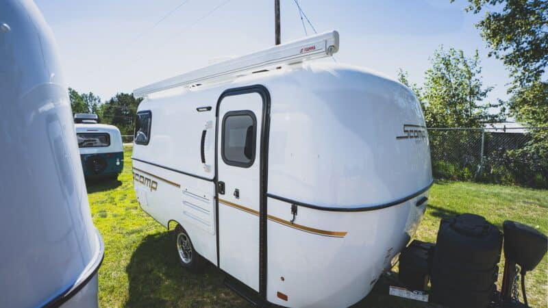 White Scamp 16 with an awning on a grassy lot