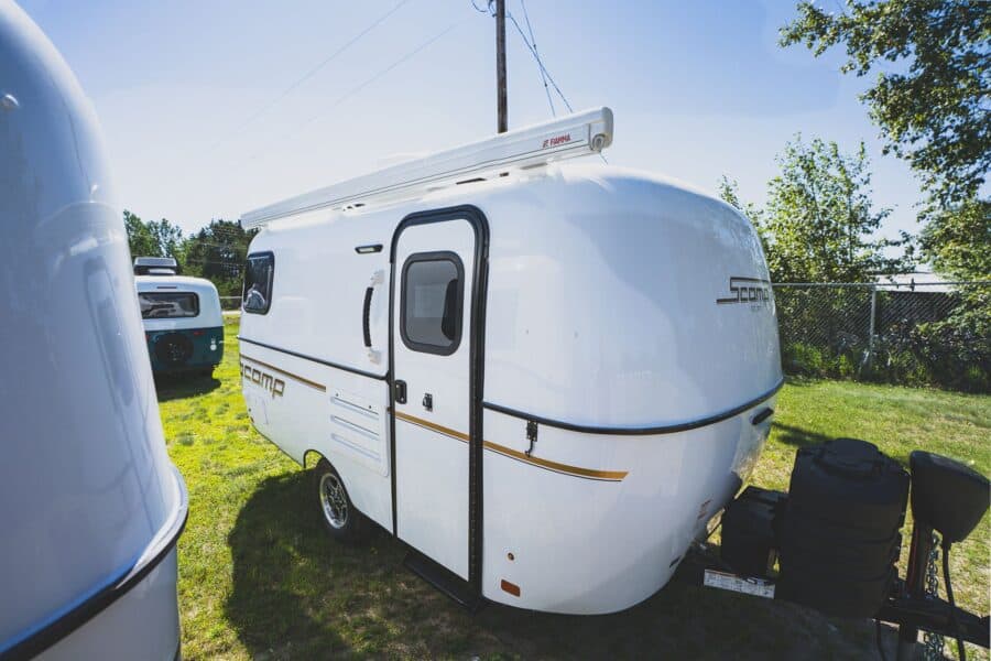 White Scamp 16 with an awning on a grassy lot