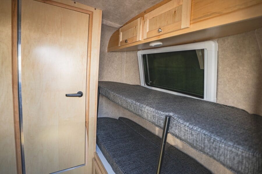Front sofa bunk with grey cushions beside the bathroom door