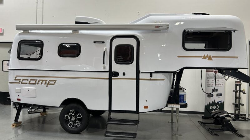 White Scamp 19 fifth wheel with an open entry step in a showroom