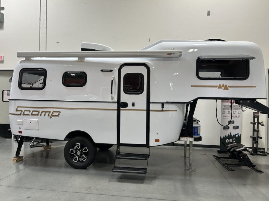 White Scamp 19 fifth wheel with an open entry step in a showroom