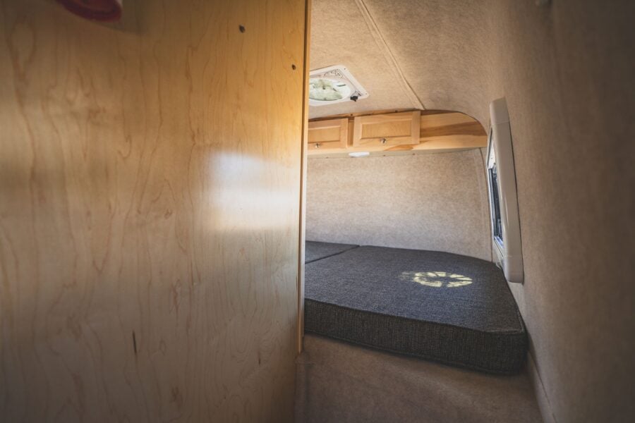 Loft bed over the hitch seen past an open wood door