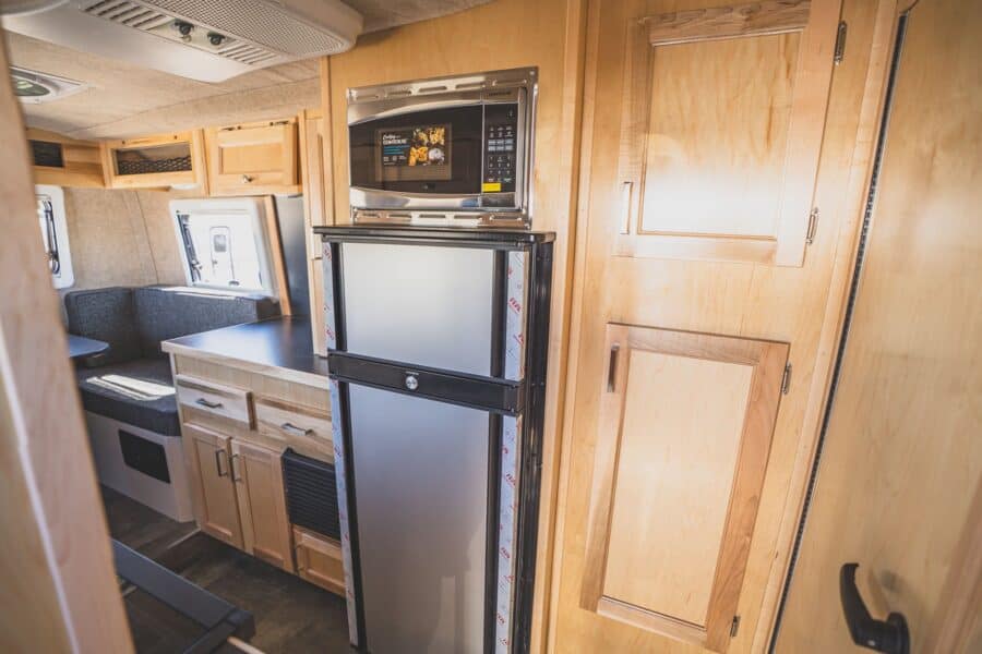 Microwave above a stainless refrigerator beside the galley